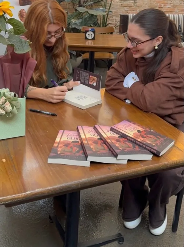 Esther Faria autografando exemplares na sessão de autógrafos